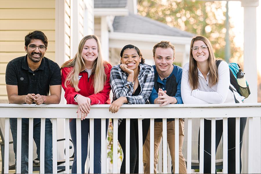 ${ 5 smiling students on porch }